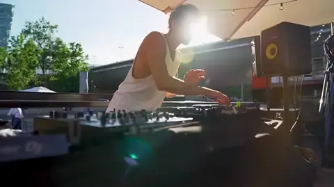 Une DJ aux platines, face à la Seine