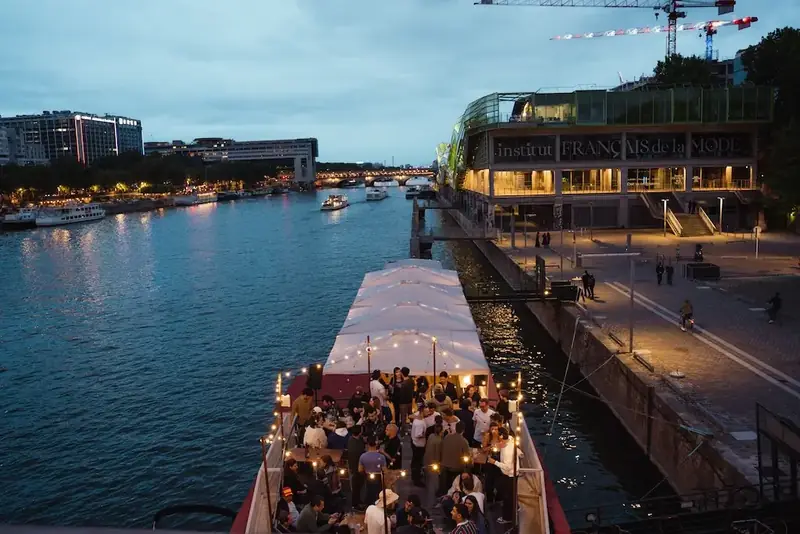 La terrasse du quai occupée par les convives, au crépuscule