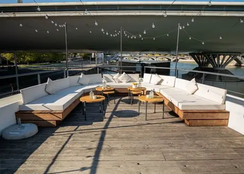 Le toit-terrasse et ses banquettes blanches, guirlandes allumées en fin de journée
